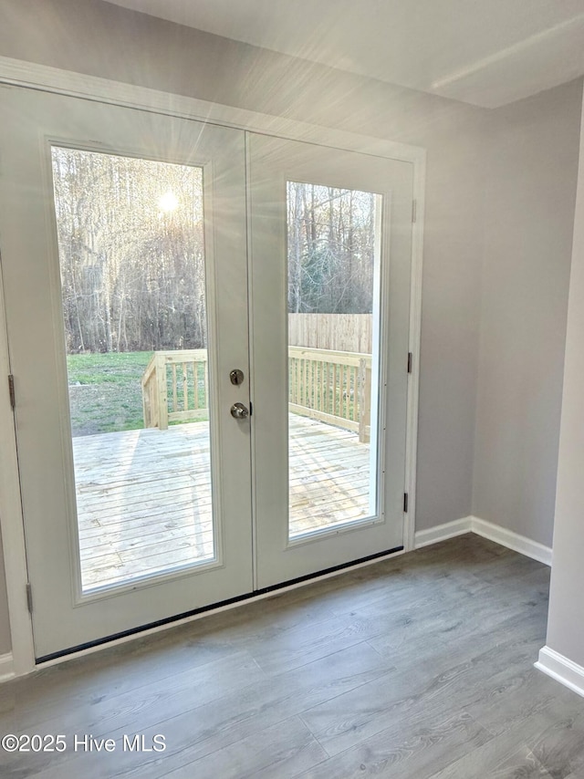 doorway with french doors, a healthy amount of sunlight, baseboards, and wood finished floors