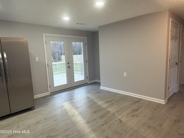 doorway featuring baseboards, visible vents, wood finished floors, and french doors