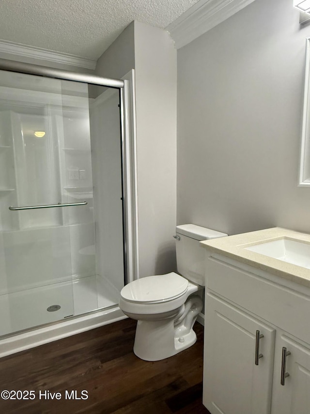 bathroom with toilet, wood finished floors, a textured ceiling, vanity, and a shower stall