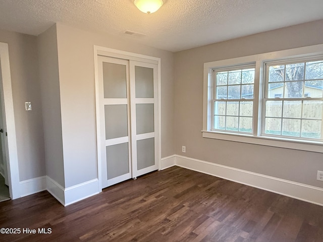 empty room with dark wood-style floors, baseboards, and a textured ceiling