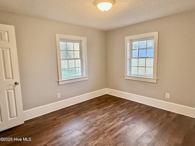 unfurnished room with a textured ceiling, dark wood-type flooring, and baseboards