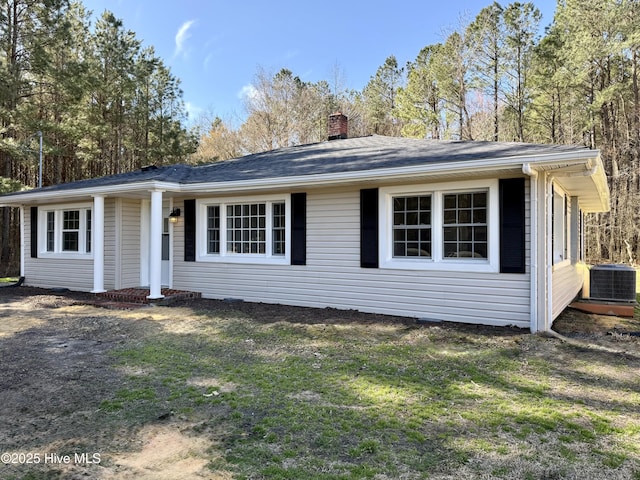 ranch-style house with a chimney, central AC unit, and a front lawn