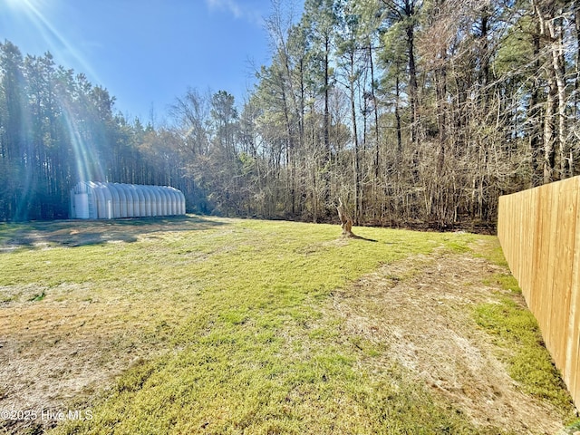 view of yard featuring fence and a wooded view