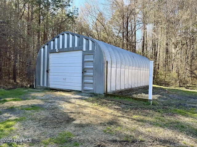 view of outdoor structure featuring an outbuilding and a wooded view