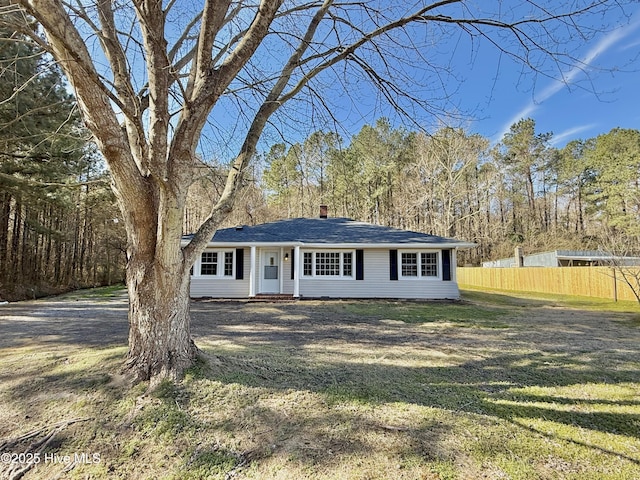 view of front of house featuring a front lawn, a chimney, and fence