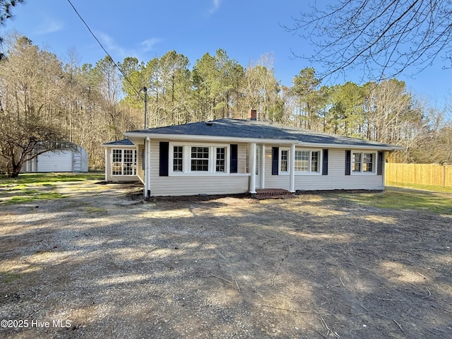 single story home with a chimney, an outdoor structure, and fence