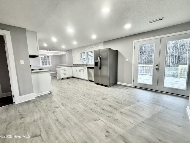 kitchen featuring light wood-style flooring, a peninsula, visible vents, french doors, and appliances with stainless steel finishes