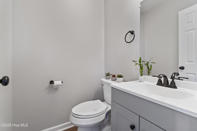 bathroom with toilet, baseboards, and vanity