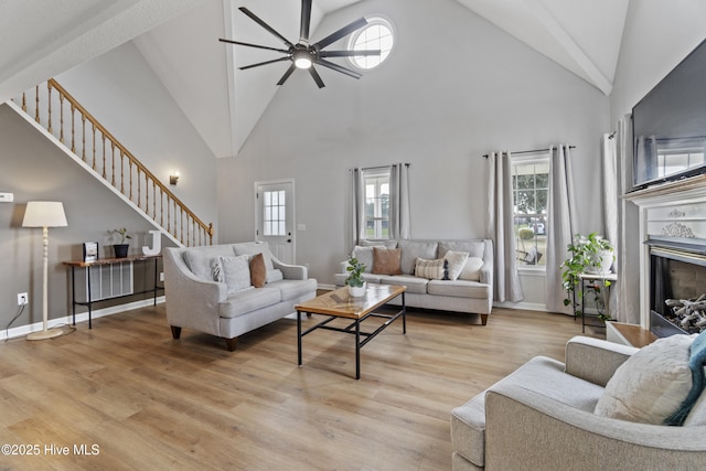 living area featuring stairs, light wood finished floors, and plenty of natural light