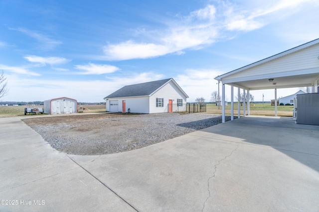 exterior space featuring a carport, an outbuilding, concrete driveway, and a shed