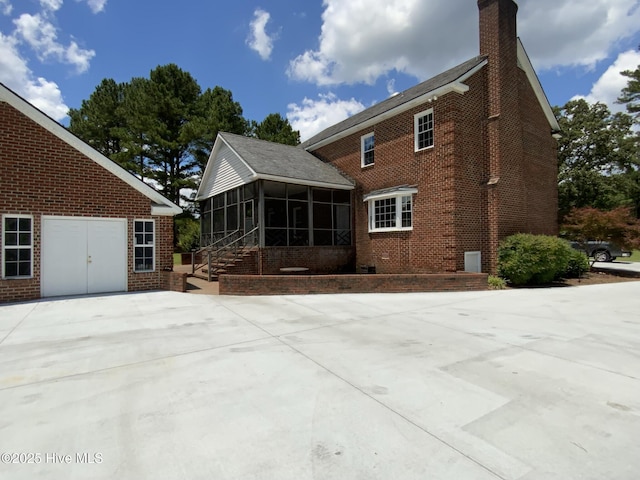 back of property with brick siding, a chimney, and a sunroom