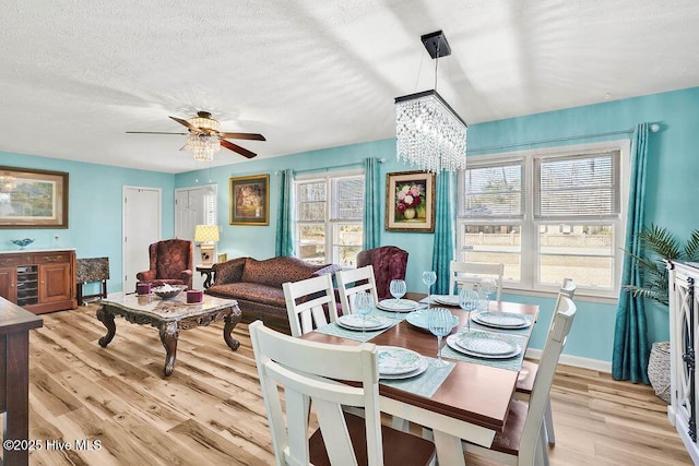 dining room with ceiling fan, baseboards, light wood finished floors, and a textured ceiling