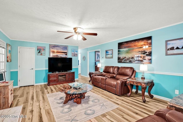 living area with a textured ceiling, a ceiling fan, light wood-style floors, and ornamental molding