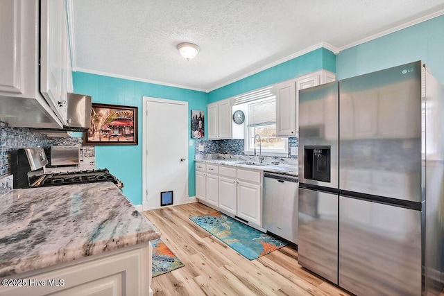 kitchen with crown molding, white cabinets, appliances with stainless steel finishes, and a sink