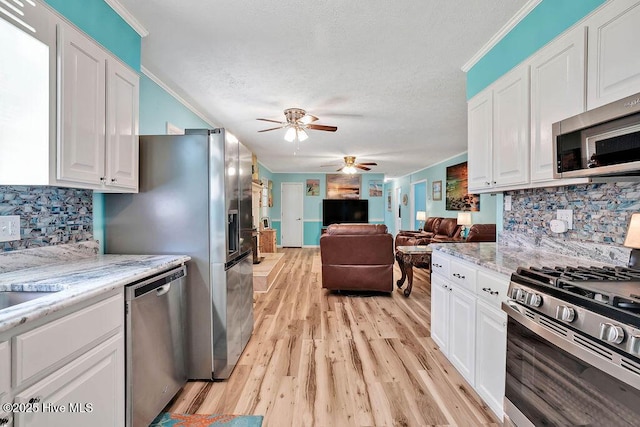 kitchen with white cabinets, appliances with stainless steel finishes, and ornamental molding