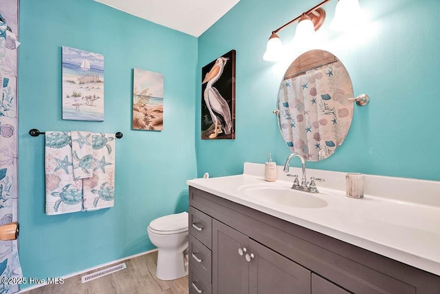 full bathroom with visible vents, toilet, vanity, and wood finished floors