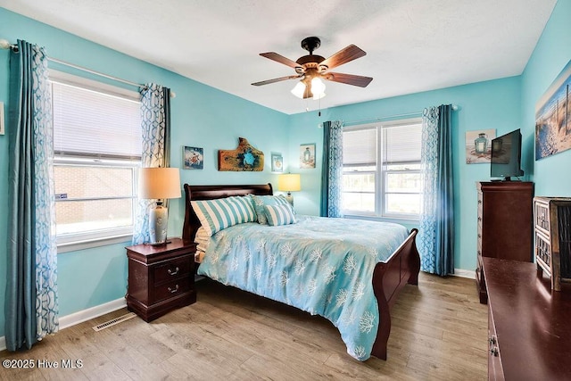 bedroom with light wood-style flooring, baseboards, and multiple windows