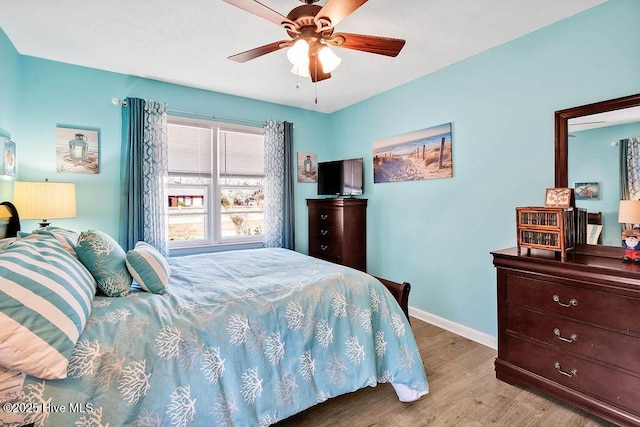 bedroom featuring ceiling fan, baseboards, and wood finished floors