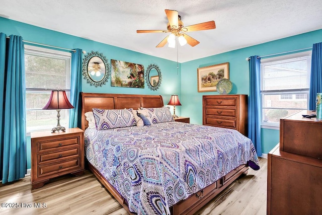 bedroom featuring ceiling fan, light wood-style flooring, baseboards, and a textured ceiling