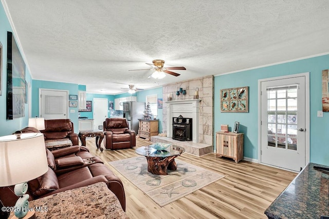 living area with crown molding, a textured ceiling, light wood-type flooring, and ceiling fan