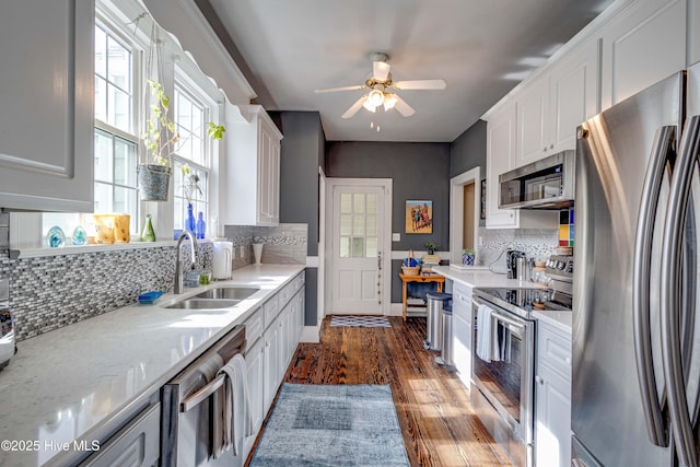 kitchen with tasteful backsplash, appliances with stainless steel finishes, dark wood-type flooring, white cabinetry, and a sink