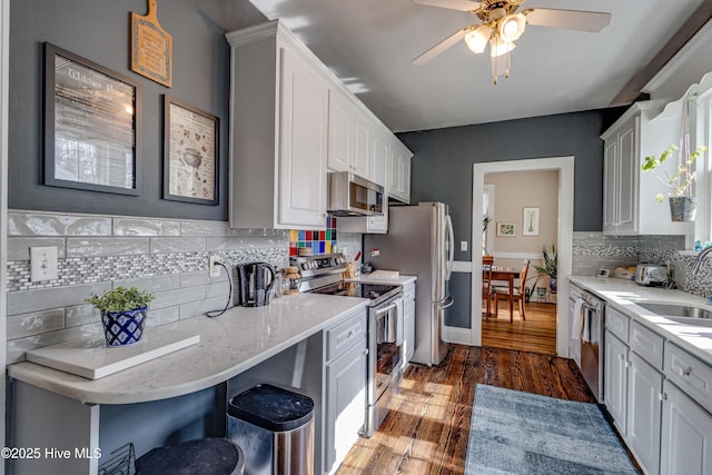 kitchen featuring dark wood-style flooring, a sink, white cabinets, appliances with stainless steel finishes, and tasteful backsplash