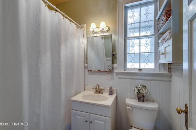 bathroom with a wainscoted wall, toilet, and vanity