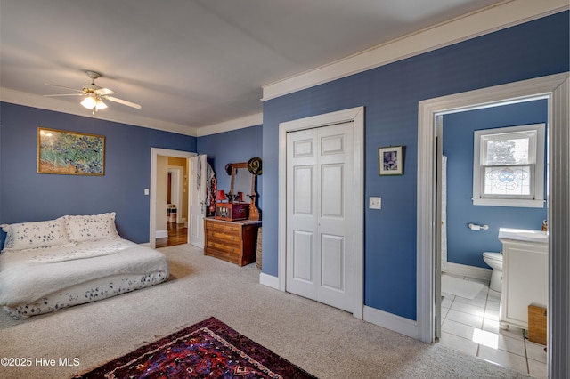 bedroom featuring ensuite bath, baseboards, a closet, and ornamental molding