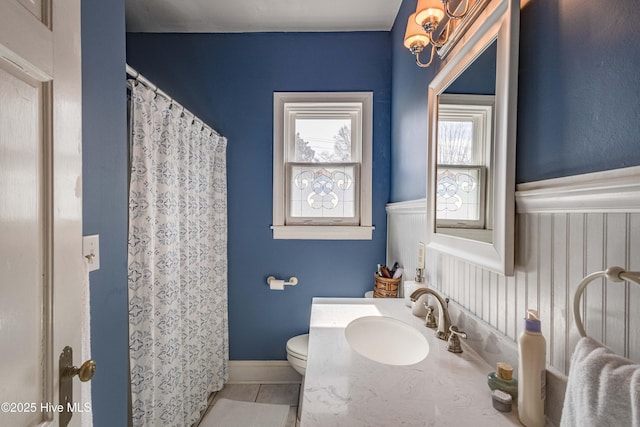 bathroom with a shower with shower curtain, toilet, wainscoting, vanity, and tile patterned flooring