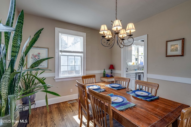 dining area with baseboards, visible vents, an inviting chandelier, and wood finished floors