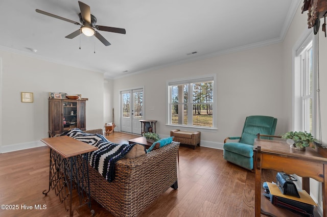 living area with visible vents, crown molding, baseboards, and wood finished floors