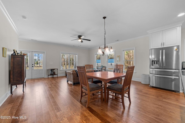 dining space with light wood-style floors, crown molding, and a wealth of natural light