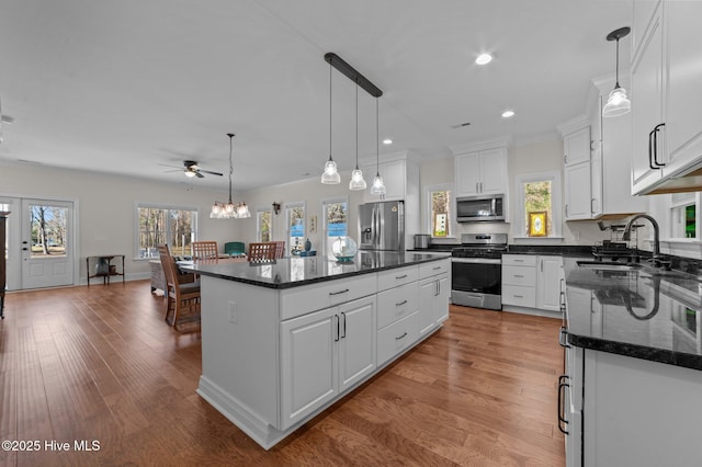 kitchen featuring stainless steel appliances, a sink, light wood-style flooring, and a center island