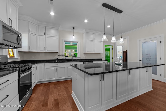 kitchen with stainless steel appliances, dark wood-type flooring, a kitchen island, a sink, and white cabinets