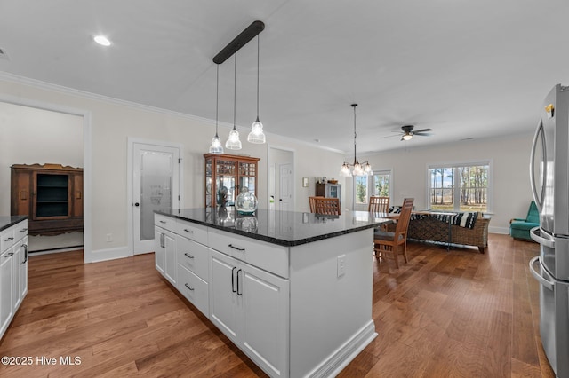 kitchen featuring ornamental molding, wood finished floors, freestanding refrigerator, and white cabinetry