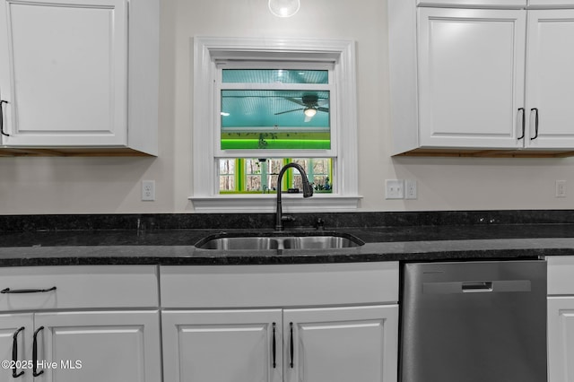 kitchen featuring dishwasher, dark stone countertops, a sink, and white cabinets