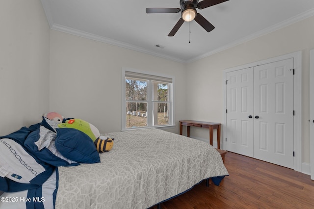 bedroom with crown molding, a closet, visible vents, ceiling fan, and wood finished floors