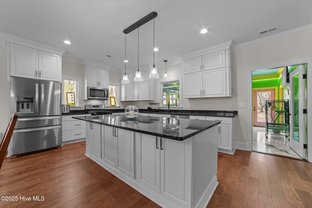 kitchen with appliances with stainless steel finishes, a center island, visible vents, and white cabinetry