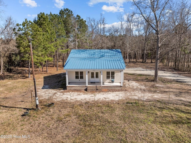 view of front of home with a forest view, metal roof, and a porch