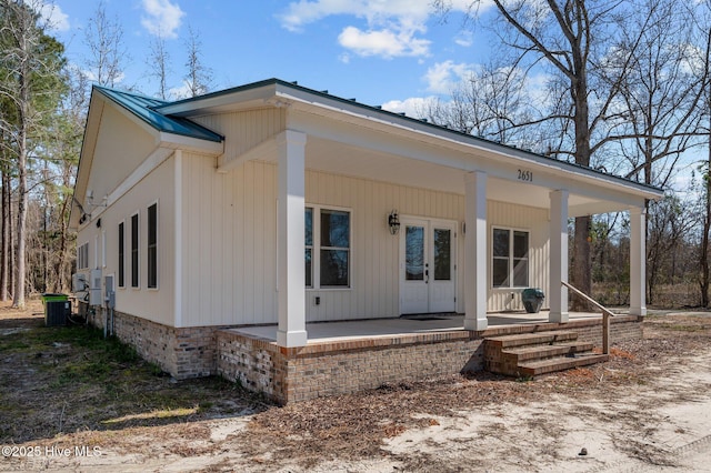 view of front facade with metal roof, a porch, and french doors