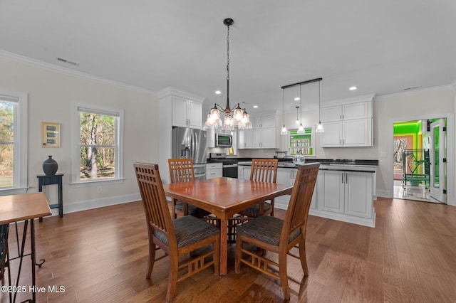 dining area featuring ornamental molding, dark wood-style flooring, and visible vents