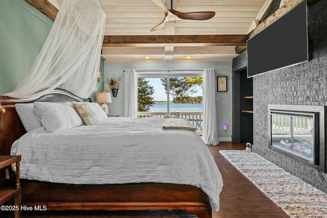 bedroom with wood finished floors, baseboards, beam ceiling, access to exterior, and a large fireplace