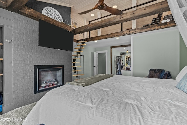 bedroom featuring a glass covered fireplace, beam ceiling, recessed lighting, and a towering ceiling