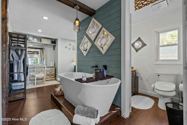 bathroom featuring wood finished floors, visible vents, baseboards, a soaking tub, and toilet