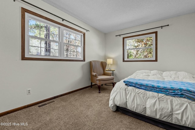 carpeted bedroom featuring visible vents, baseboards, and a textured ceiling