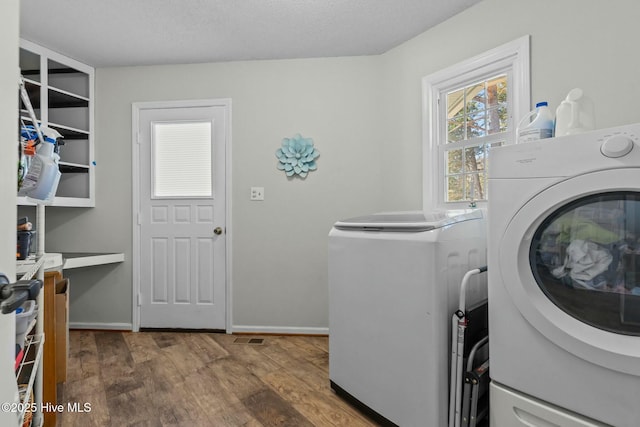 laundry area featuring wood finished floors, baseboards, laundry area, a textured ceiling, and washer and dryer