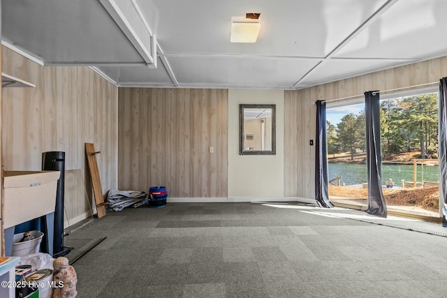 unfurnished room featuring tile patterned floors, baseboards, wood walls, and a water view