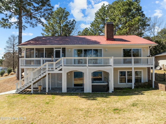 rear view of house featuring a lawn, stairway, a sunroom, metal roof, and a chimney