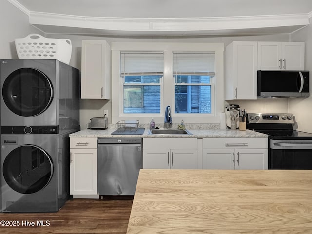 kitchen featuring a sink, light countertops, stacked washer and dryer, white cabinets, and appliances with stainless steel finishes