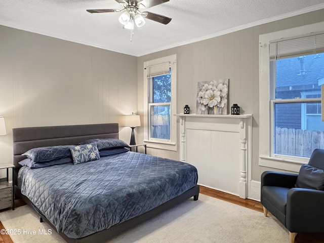 bedroom with ceiling fan, a textured ceiling, wood finished floors, and crown molding